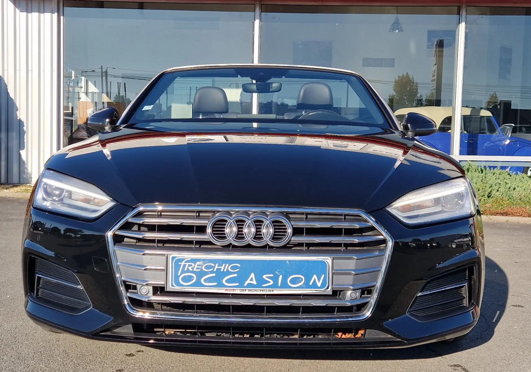Vue frontale d'une Audi A5 Cabriolet noire de 2017 avec calandre chromée et phares LED allumés.