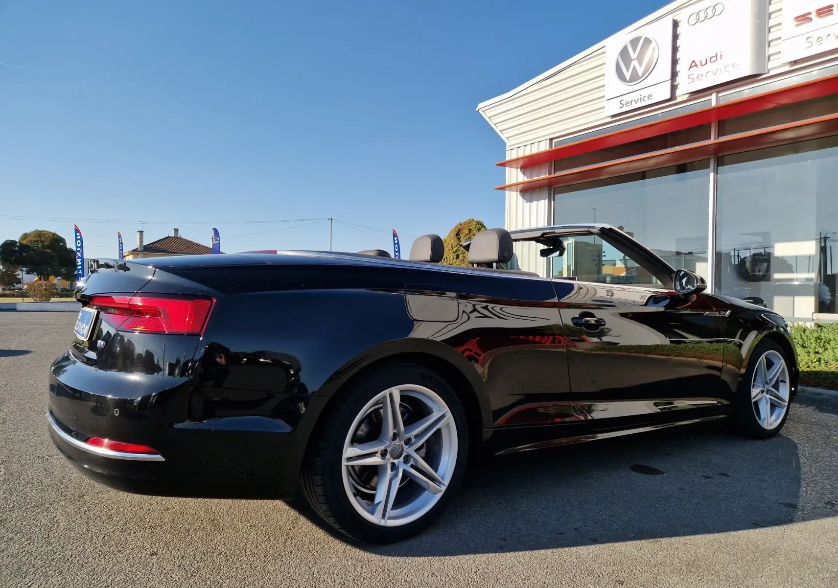 Audi A5 Cabriolet noir vue de profil côté gauche, capote ouverte, jantes alliage et feux arrière LED visibles.
