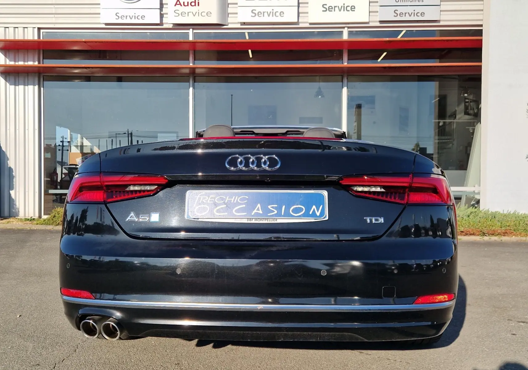 Vue arrière d'une Audi A5 Cabriolet noire de 2017 avec double sortie d'échappement et feux LED allumés.