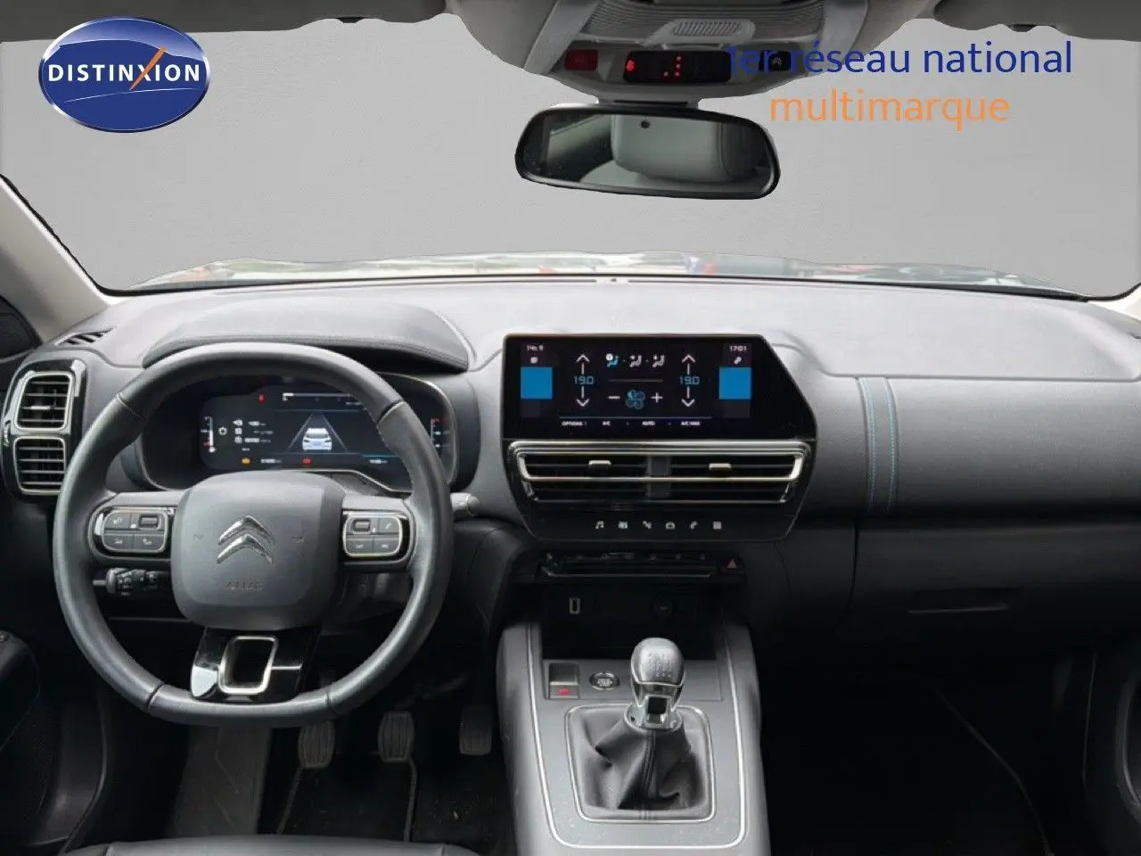 Vue intérieure frontale du tableau de bord et volant du Citroën C5 Aircross gris platinium, avec boîte manuelle et écran tactile central.