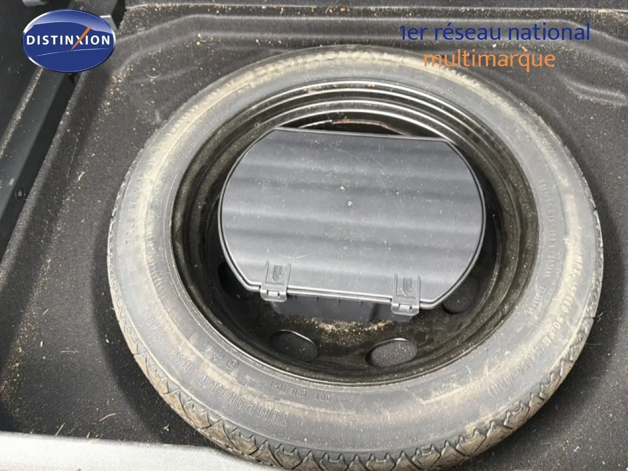 Vue plongeante sur la roue de secours et le compartiment de rangement dans le coffre du Citroën C5 Aircross gris platinium.