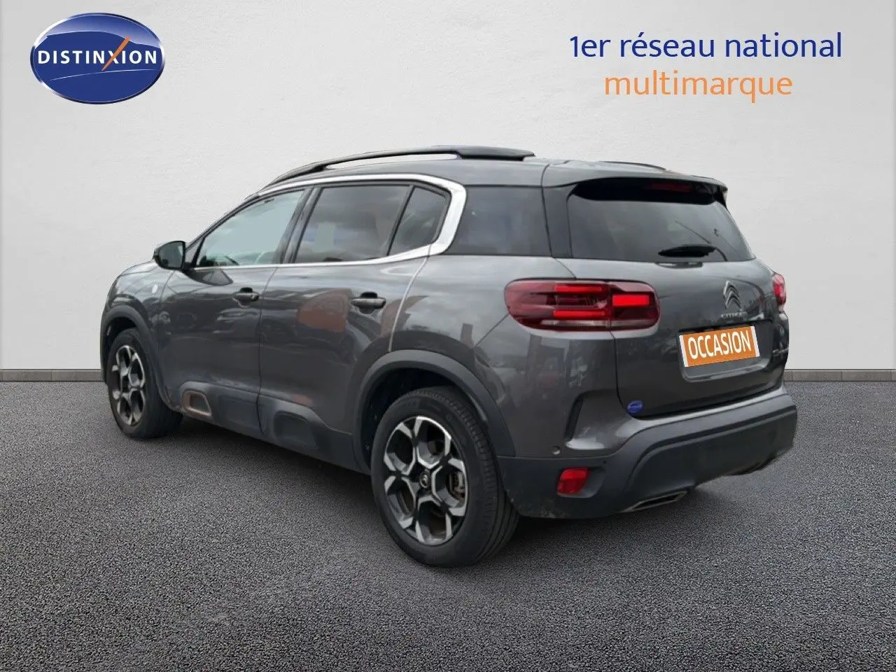 Vue 3/4 arrière droite d'un Citroën C5 Aircross gris platinium avec jantes bi-ton et toit noir.