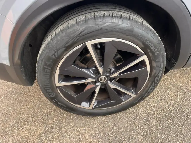 Gros plan sur la roue avant droite du Nissan Qashqai 2022 gris argile avec jante alliage noire et argentée.