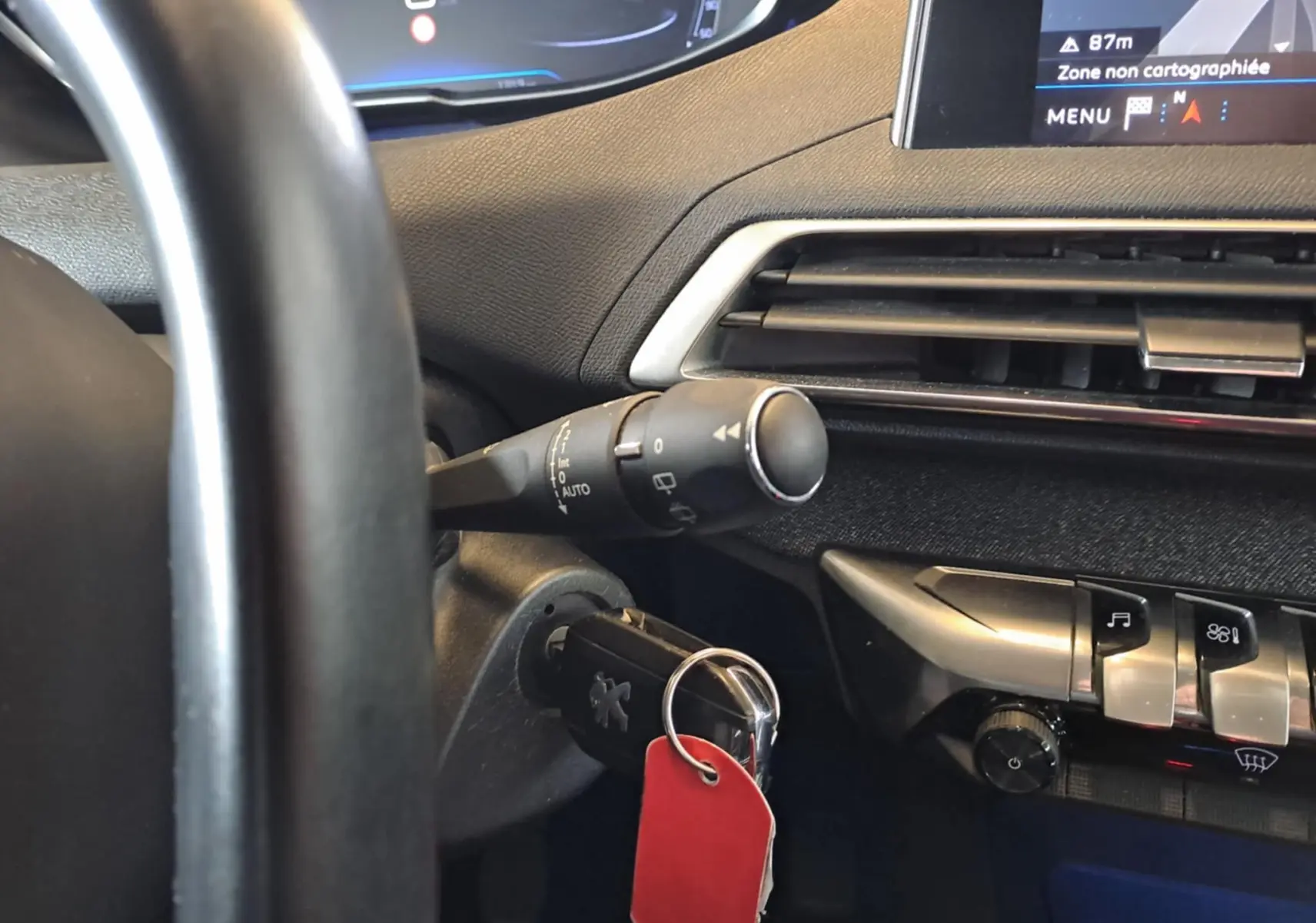 Vue rapprochée du tableau de bord côté gauche du Peugeot 3008 gris Artense avec clé insérée et commandes visibles.