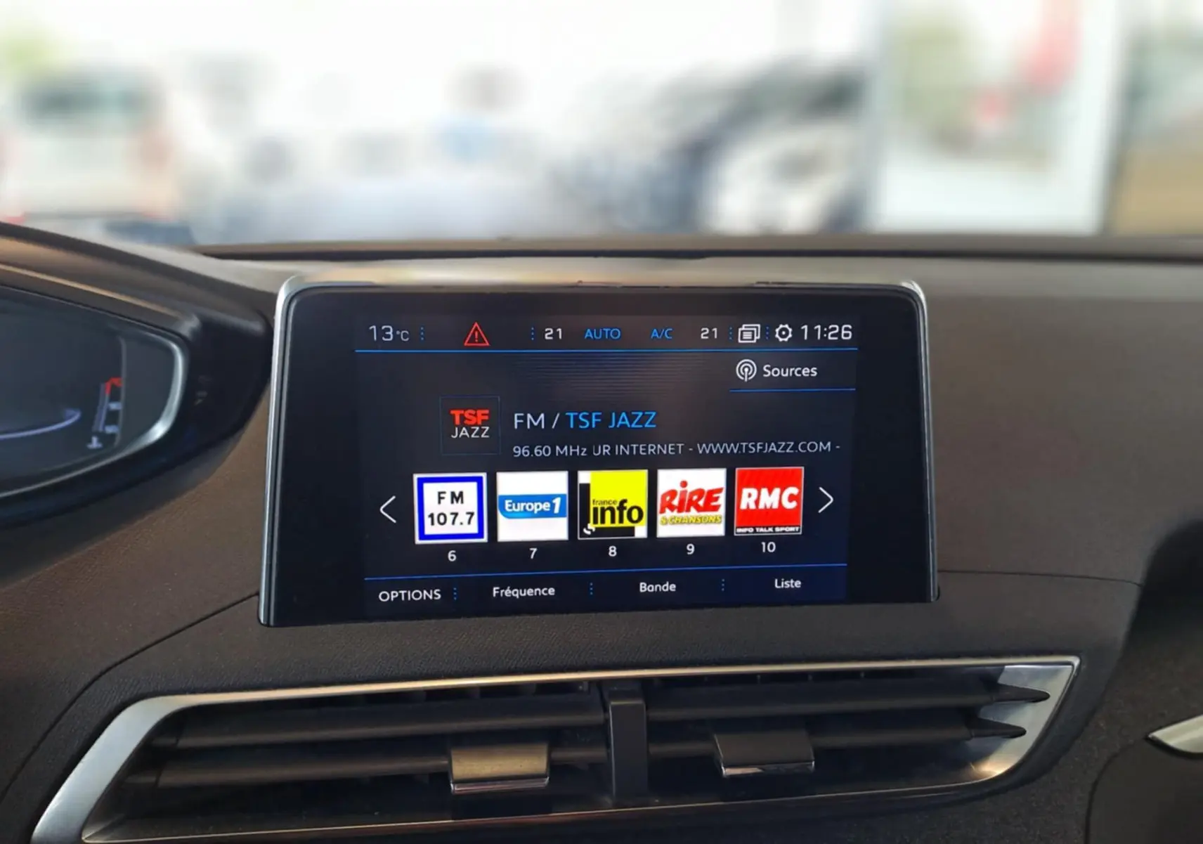 Écran central tactile du tableau de bord du Peugeot 3008 gris Artense affichant les stations radio FM avec interface moderne.