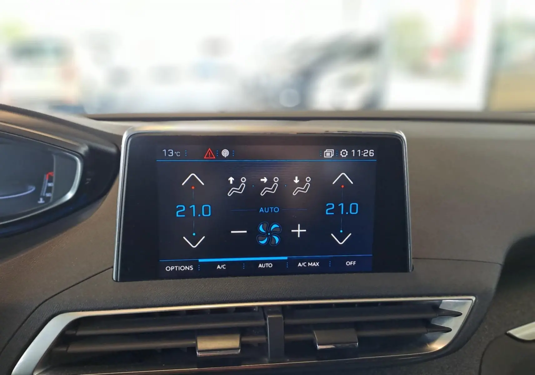 Écran tactile central du tableau de bord du Peugeot 3008 gris, affichant la climatisation à 21°C en mode automatique.