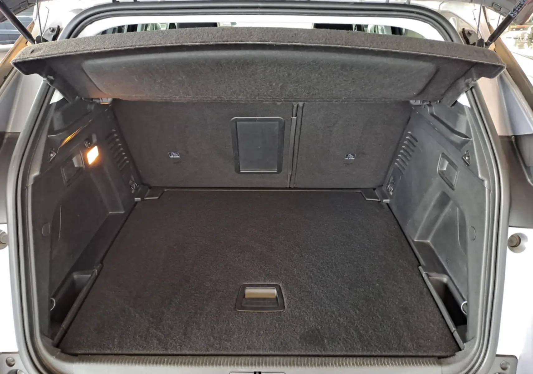 Coffre ouvert vu de l'arrière du Peugeot 3008 gris Artense, montrant un espace de chargement propre et bien éclairé.