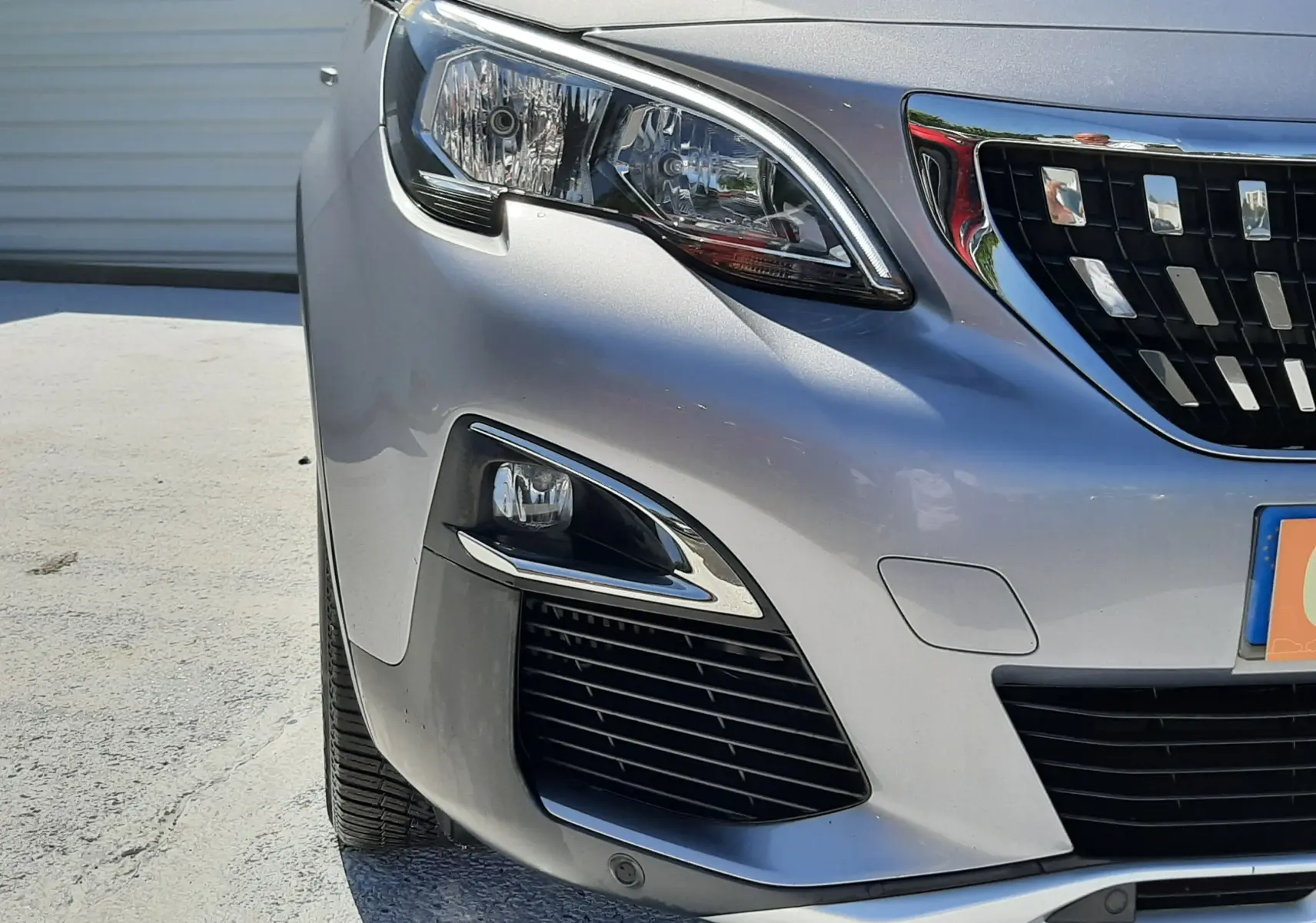 Vue de face côté gauche d'un Peugeot 3008 gris Artense mettant en valeur ses phares et sa calandre chromée.