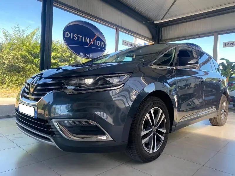 Vue 3/4 avant droite d'un Renault Espace V gris métallisé en showroom avec jantes alliage et feux LED distinctifs.