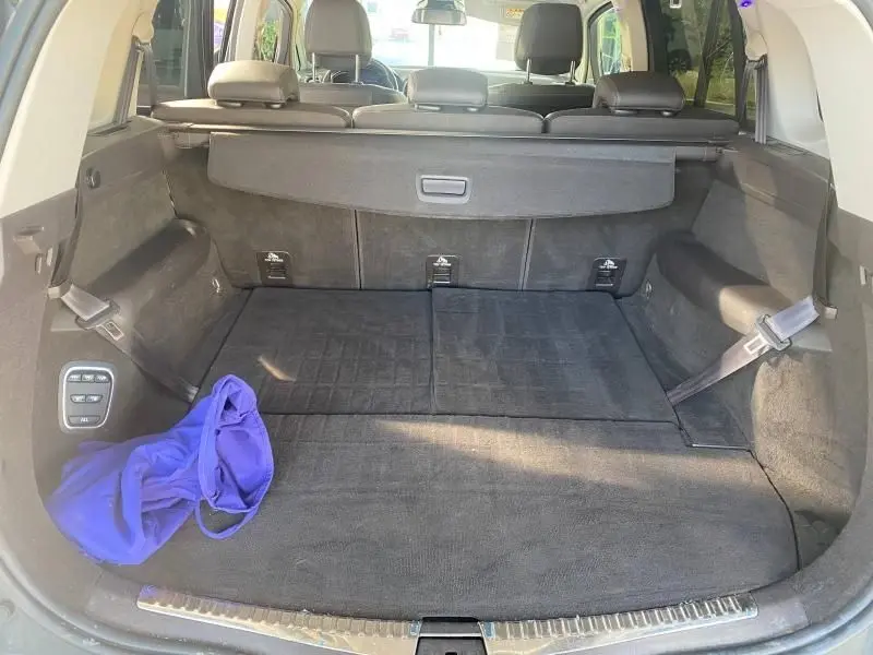 Coffre ouvert vu de l'arrière d'un Renault Espace V gris, avec banquette arrière rabattue et sac bleu à gauche.