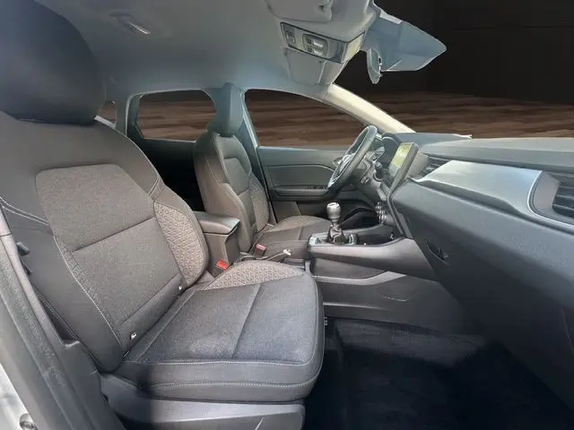 Vue intérieure côté conducteur du Renault Captur TCe 90 Evolution 2024 avec sièges tissu noir et tableau de bord moderne.