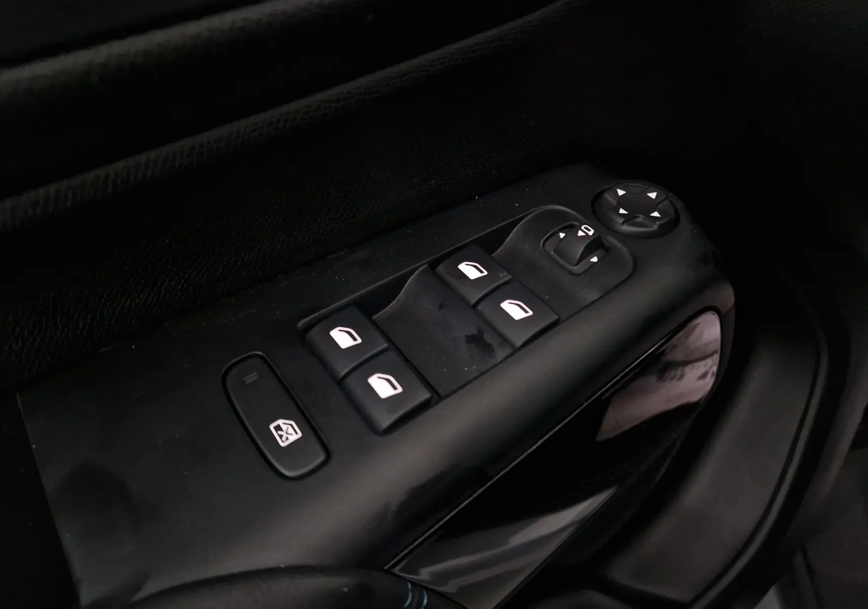Gros plan sur les commandes de lève-vitres côté gauche du Citroën C5 Aircross gris 2024 avec finition noire intérieure.