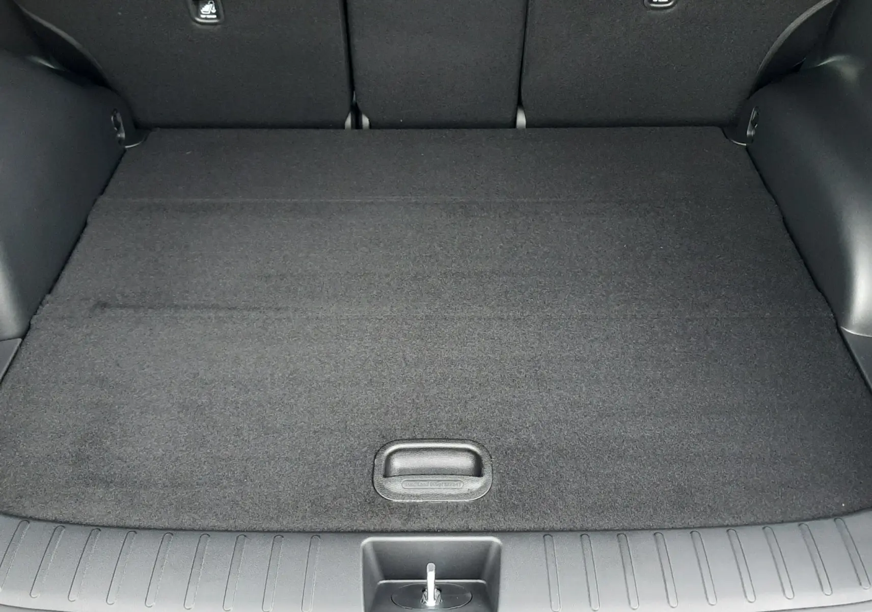 Vue intérieure du coffre du Hyundai Tucson 2025 gris Ecotronic, montrant le hayon électrique ouvert et l'espace de chargement vide.