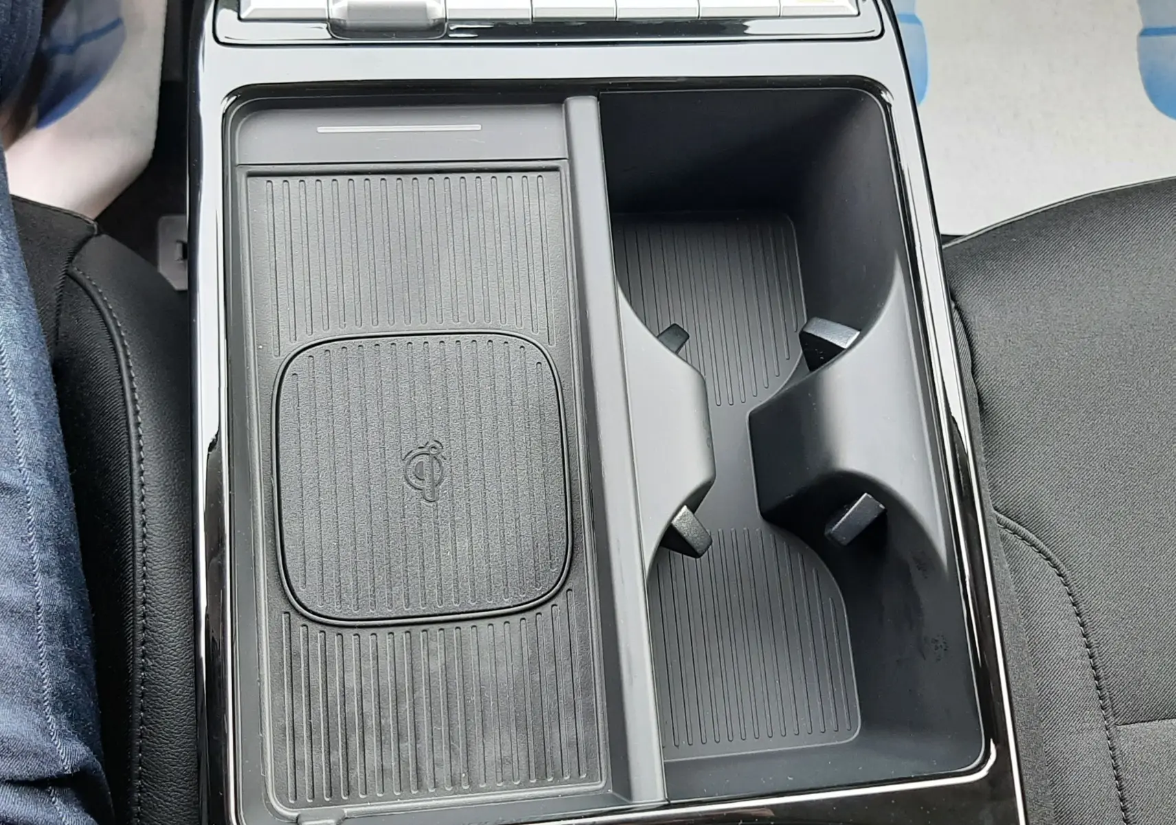 Vue plongeante sur la console centrale noire du Hyundai Tucson 2025, avec zone de recharge sans fil et porte-gobelets.