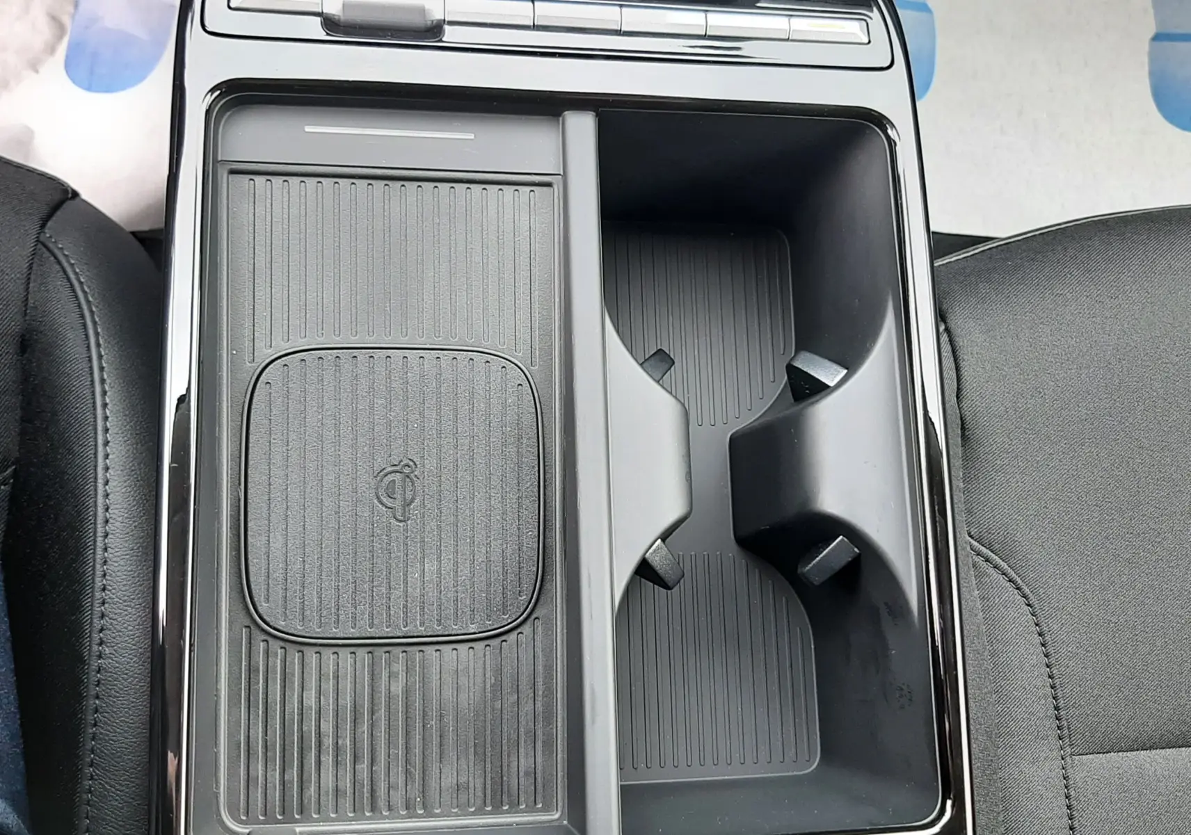 Vue plongeante sur la console centrale noire du Hyundai Tucson 2025, avec rangement et zone de recharge sans fil Qi.