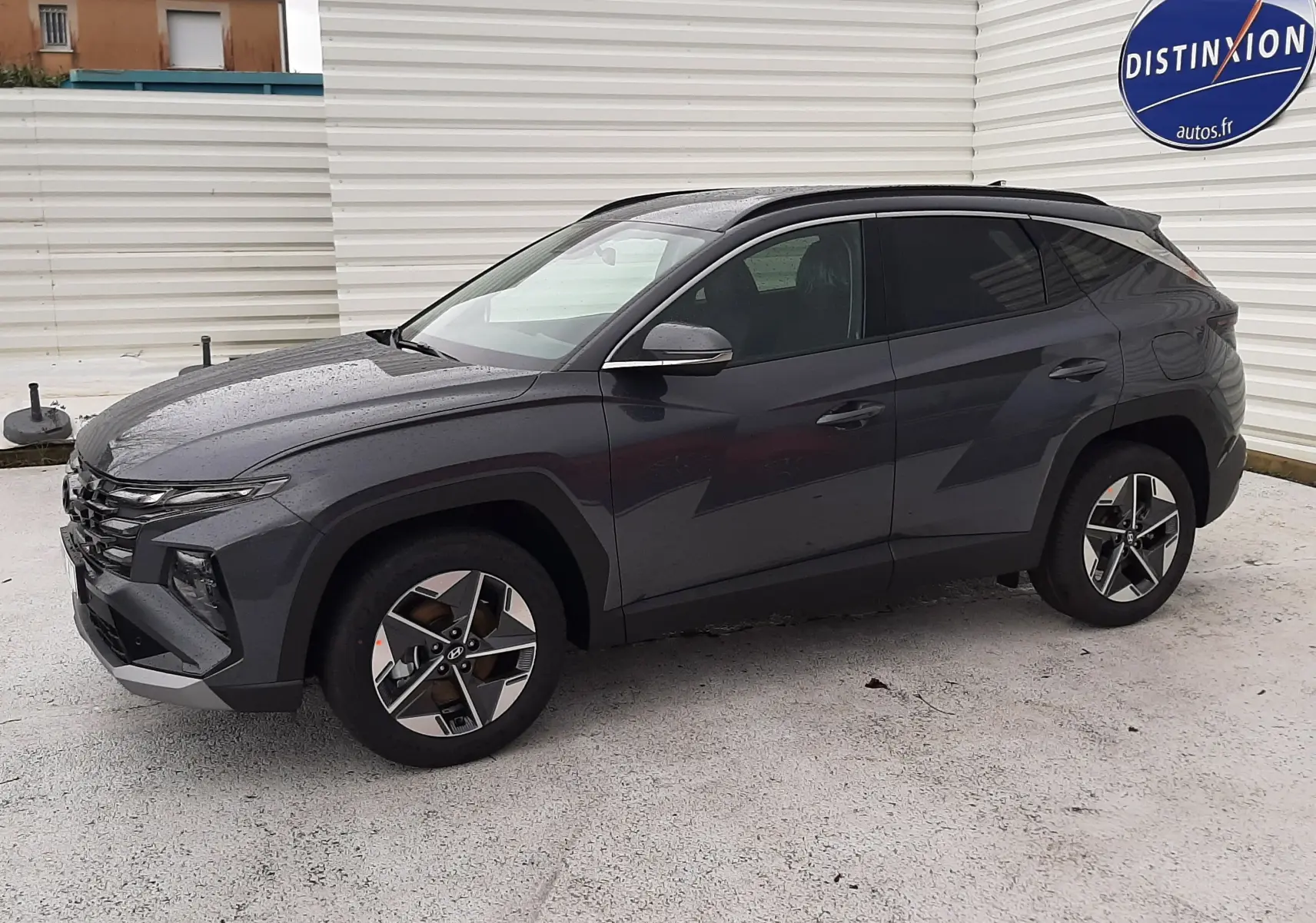 Vue de profil côté gauche du Hyundai Tucson 2025 gris Ecotronic, avec jantes alliage et toit noir contrasté.
