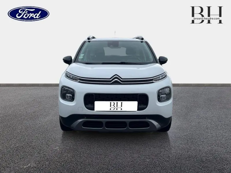 Vue de face du Citroën C3 Aircross blanc Natural White avec calandre noire et barres de toit visibles.