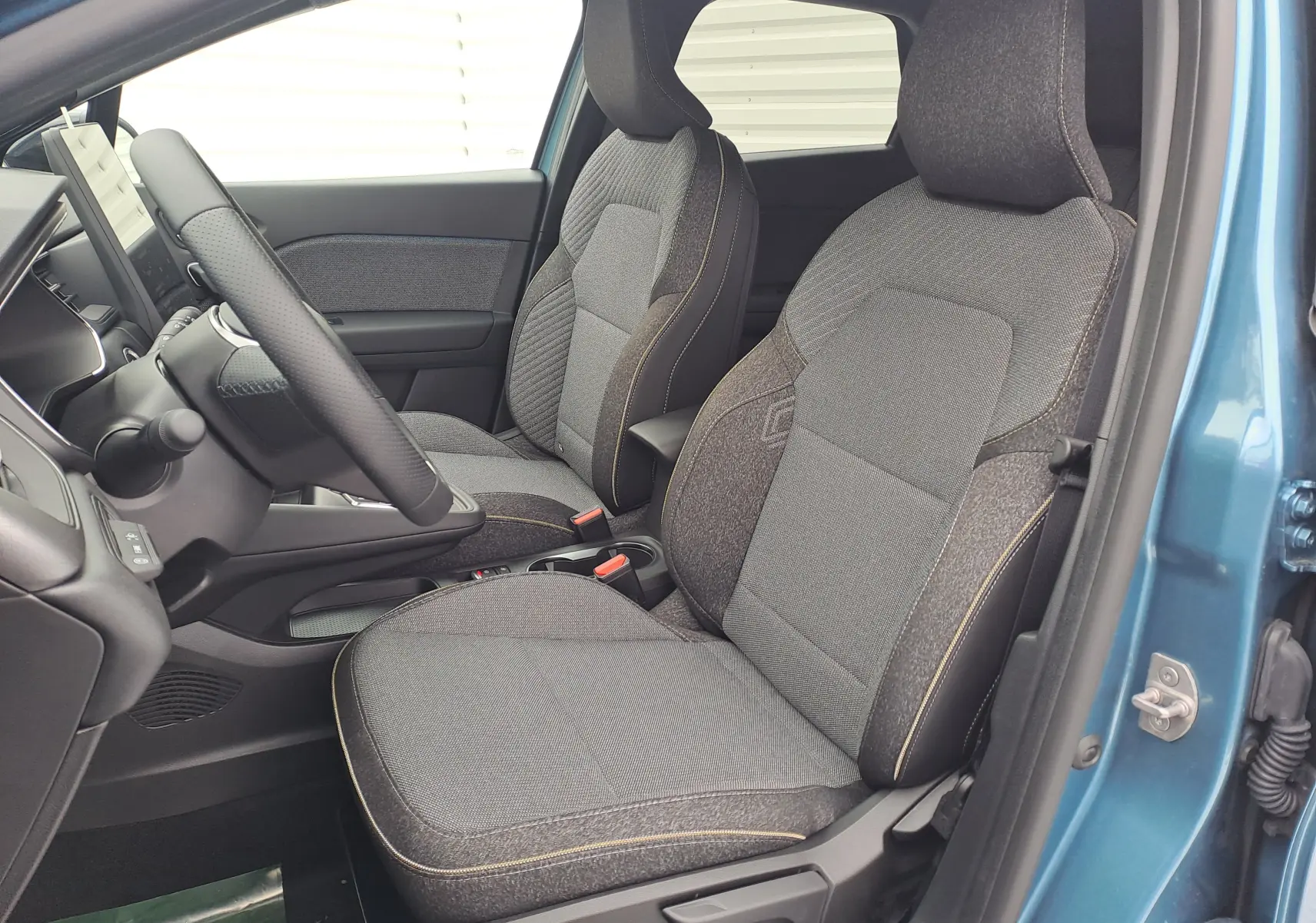 Intérieur côté conducteur du Renault Symbioz bleu mercure 2025, sièges tissu Techno gris avec surpiqûres jaunes.
