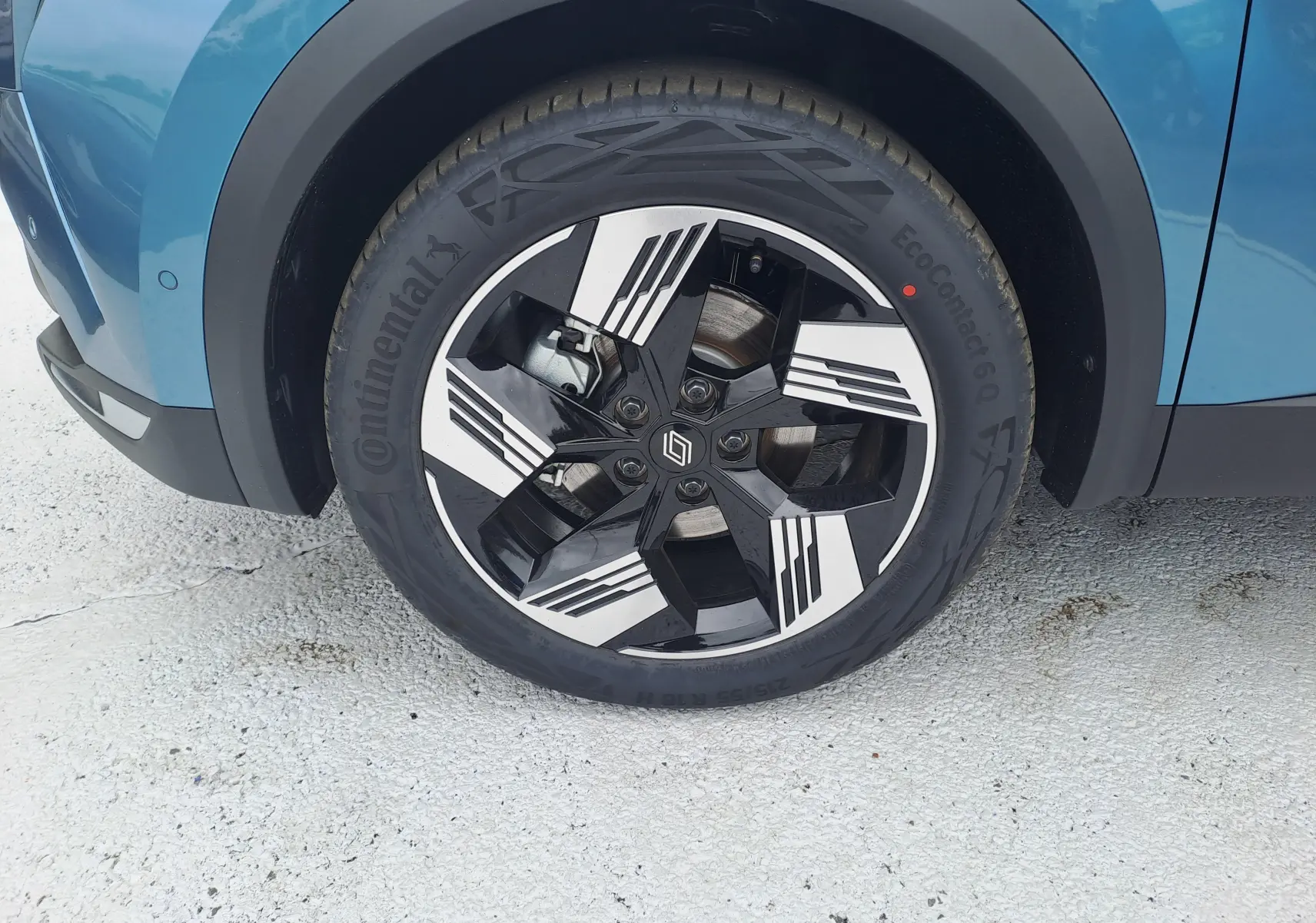 Gros plan sur la roue avant gauche du Renault Symbioz bleu mercure avec jante alliage noire et blanche design géométrique.