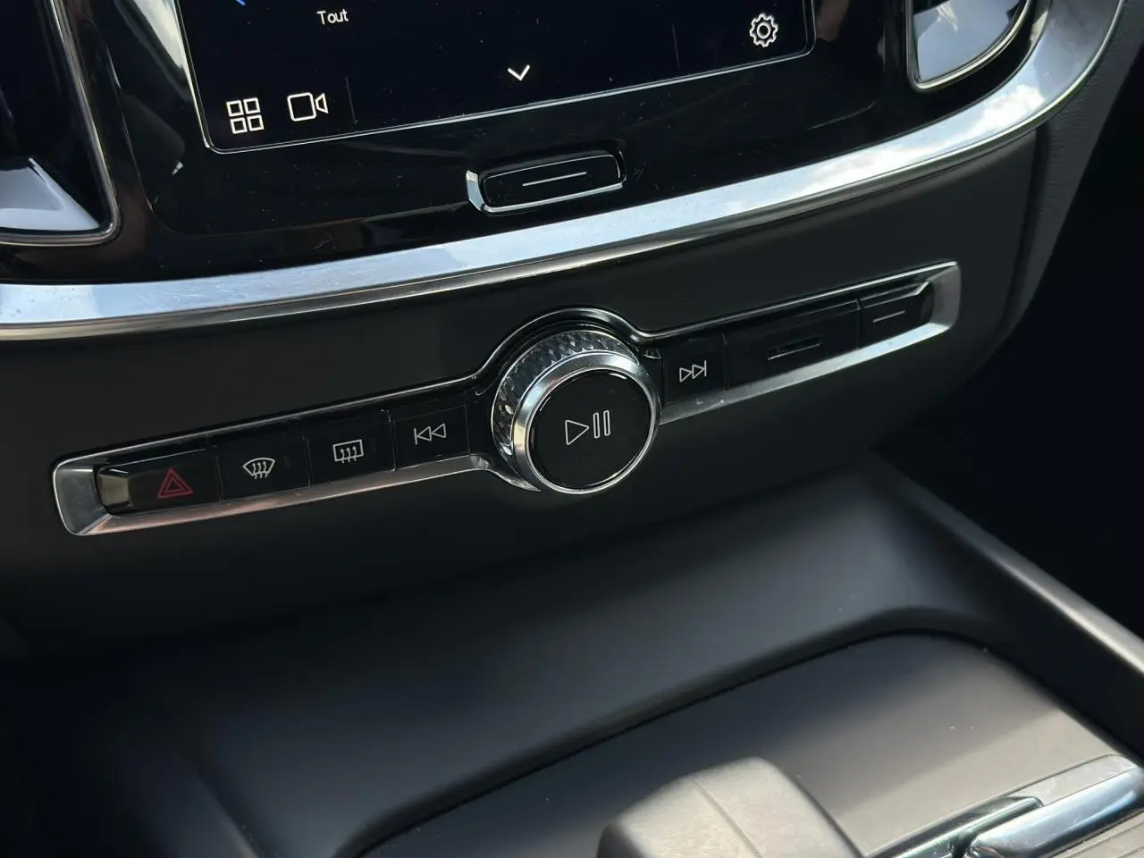 Bouton central de contrôle multimédia et commandes audio sur la console d'une Volvo S60 rouge Fusion 2024.