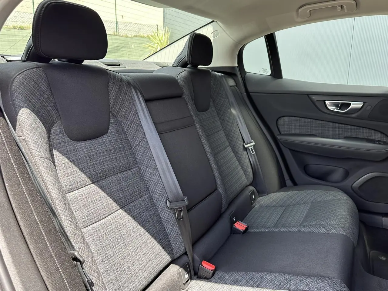 Vue intérieure de la banquette arrière grise à motifs de la Volvo S60 2024, côté droit avec ceinture de sécurité visible.