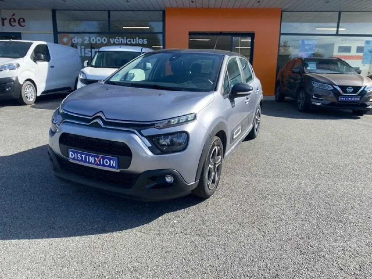 Citroën C3 gris Artense métal vue 3/4 avant droit avec phares LED et enjoliveurs 3D sur parking extérieur.