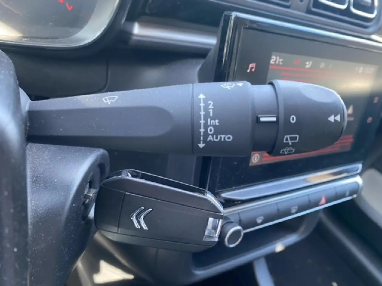 Gros plan sur la commande d'essuie-glace et la clé noire avec logo Citroën dans l'habitacle du C3 gris Artense.