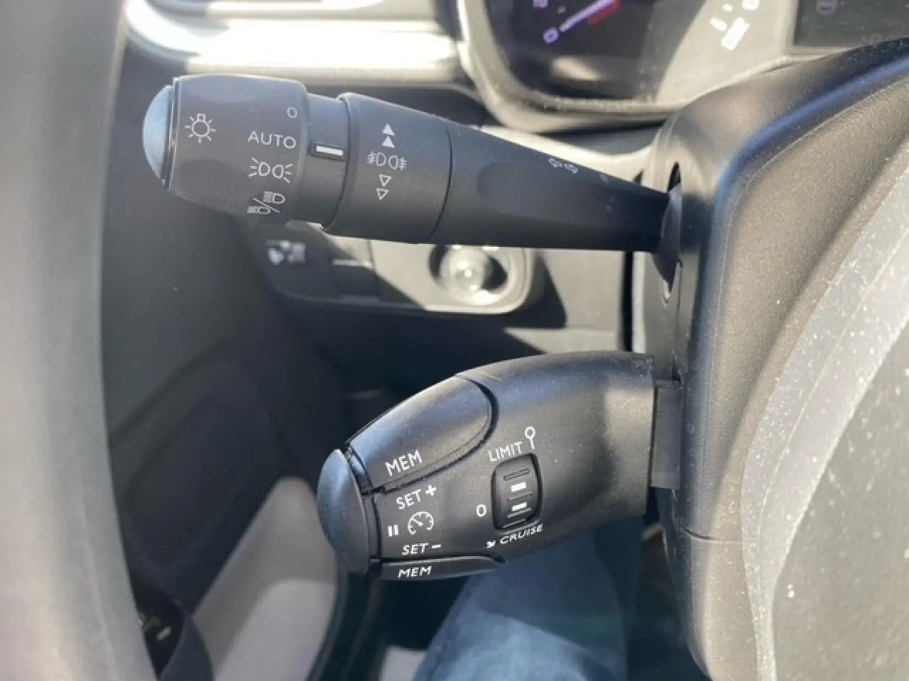 Gros plan sur les commandes de régulateur de vitesse et éclairage du tableau de bord d'une Citroën C3 gris Artense 2022.