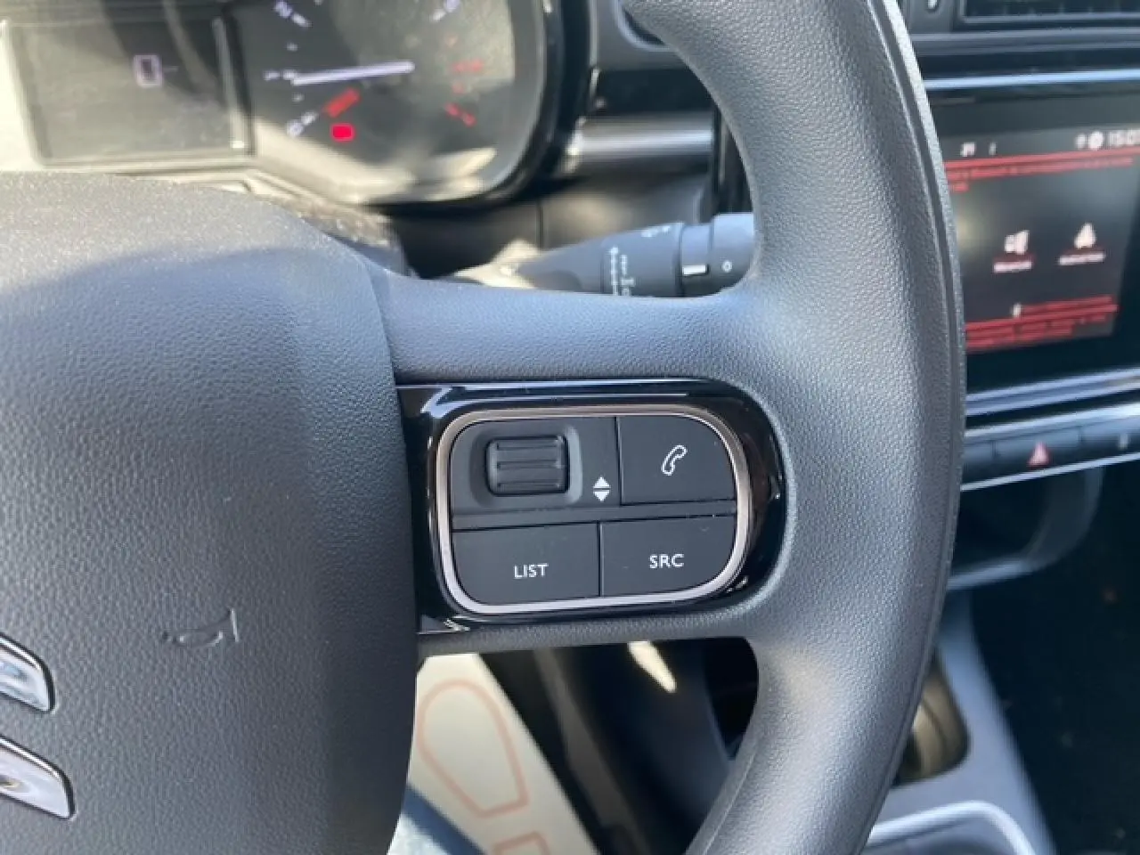Gros plan sur les commandes du volant du Citroën C3 1.2 83 Shine 2022, intérieur noir avec écran tactile visible.