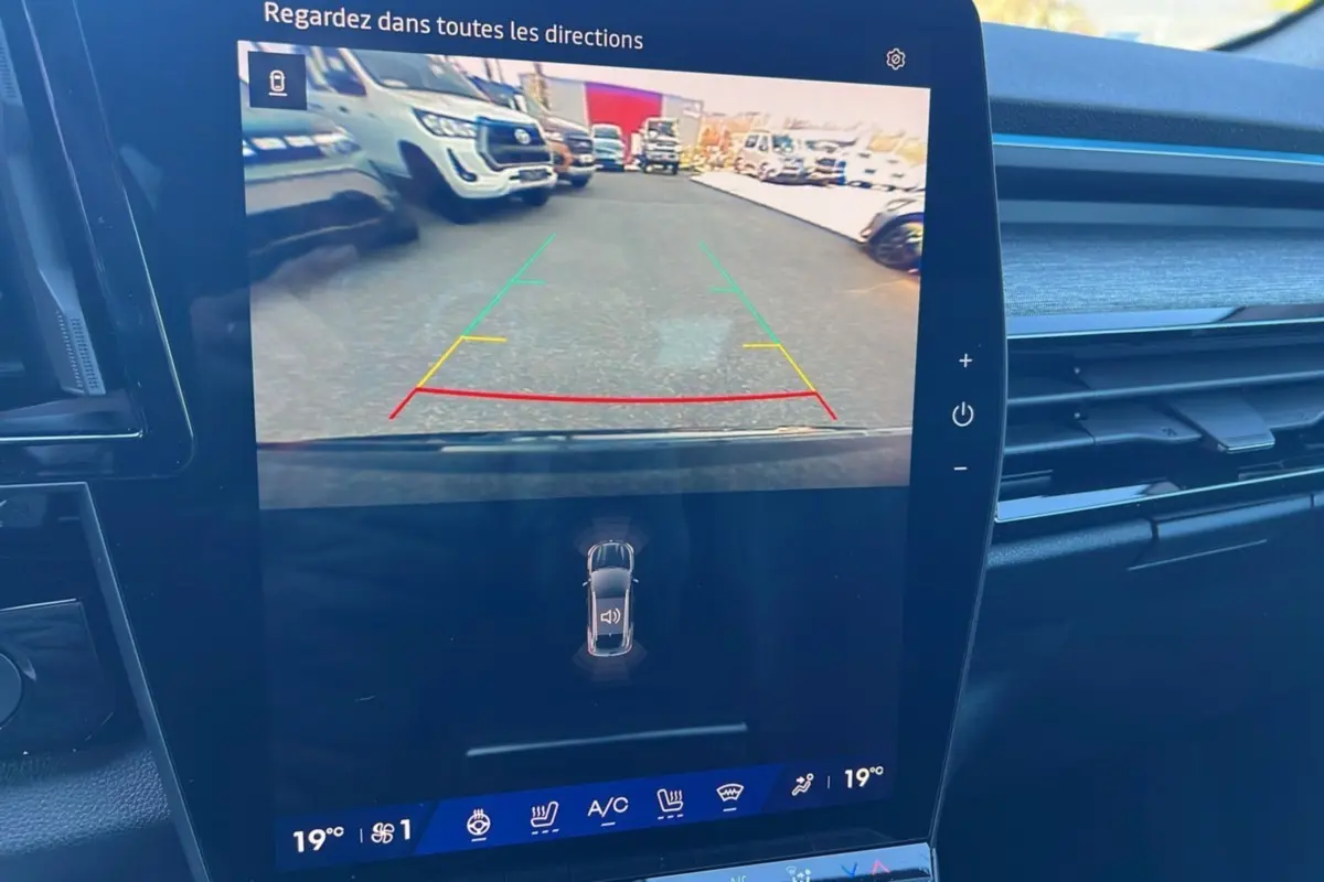 Écran central du Renault Austral E-Tech 200 Techno 2025 montrant la caméra de recul avec vue arrière et lignes de guidage colorées.