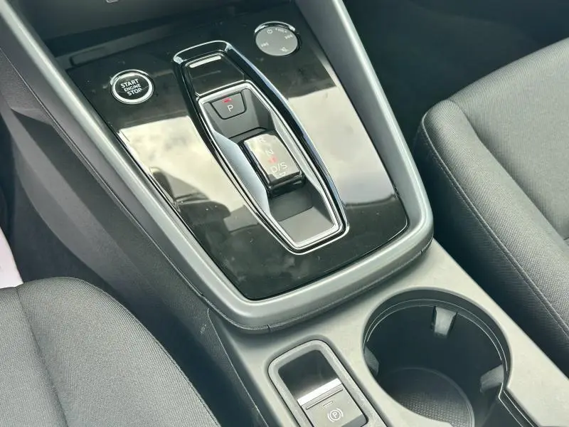 Console centrale noire brillante avec levier de boîte auto et bouton start/stop dans l'Audi A3 Sportback 2024.