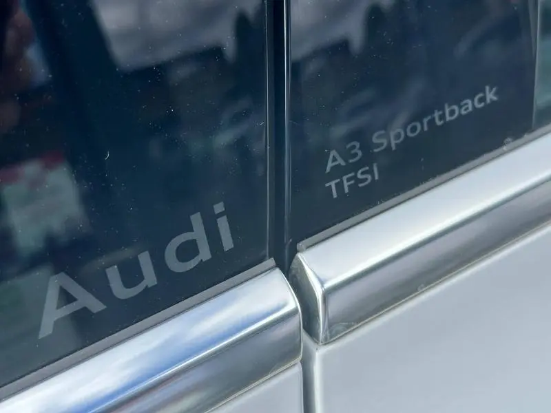 Gros plan sur les inscriptions Audi et A3 Sportback TFSI sur une porte argentée du véhicule.