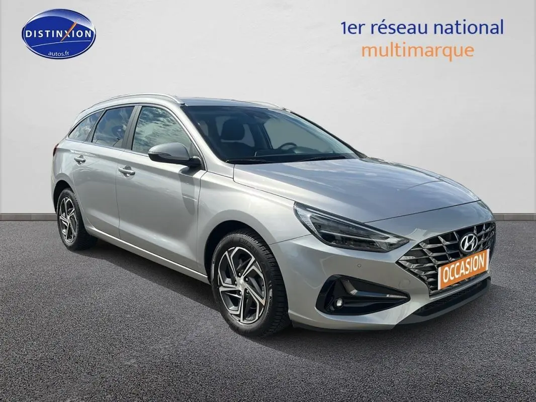 Hyundai i30 SW gris clair vue 3/4 avant droit avec jantes alliage et calandre distinctive moderne