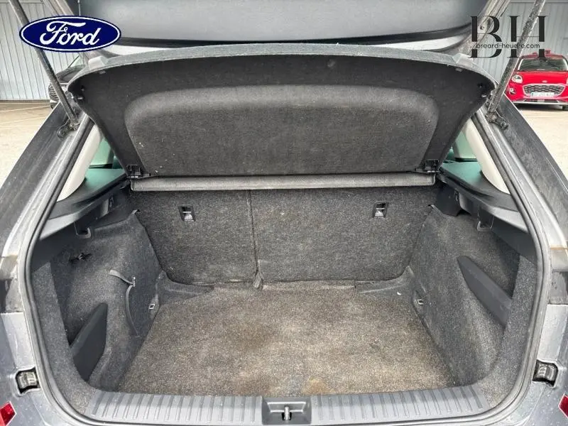 Coffre ouvert vu de l'arrière d'un Skoda Kamiq gris graphite métallisé, montrant l'espace de chargement vide et la tablette cache-bagages.