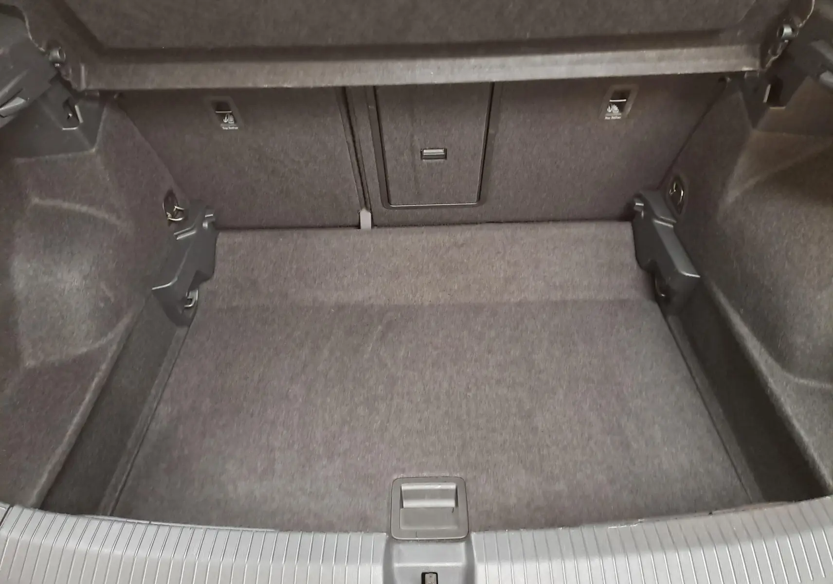 Coffre vide du Volkswagen T-Roc 1.5 TSI 150 DSG7 en vue plongeante, montrant la moquette et les fixations internes.