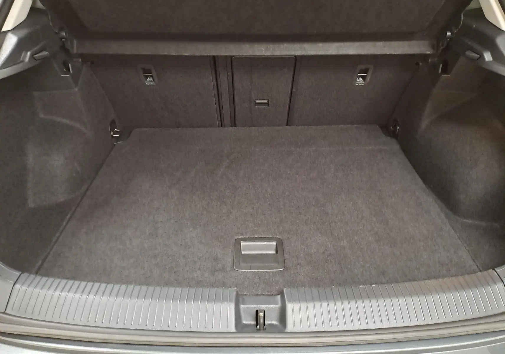 Coffre ouvert du Volkswagen T-Roc 1.5 TSI gris Indium, montrant un espace de chargement propre et spacieux.