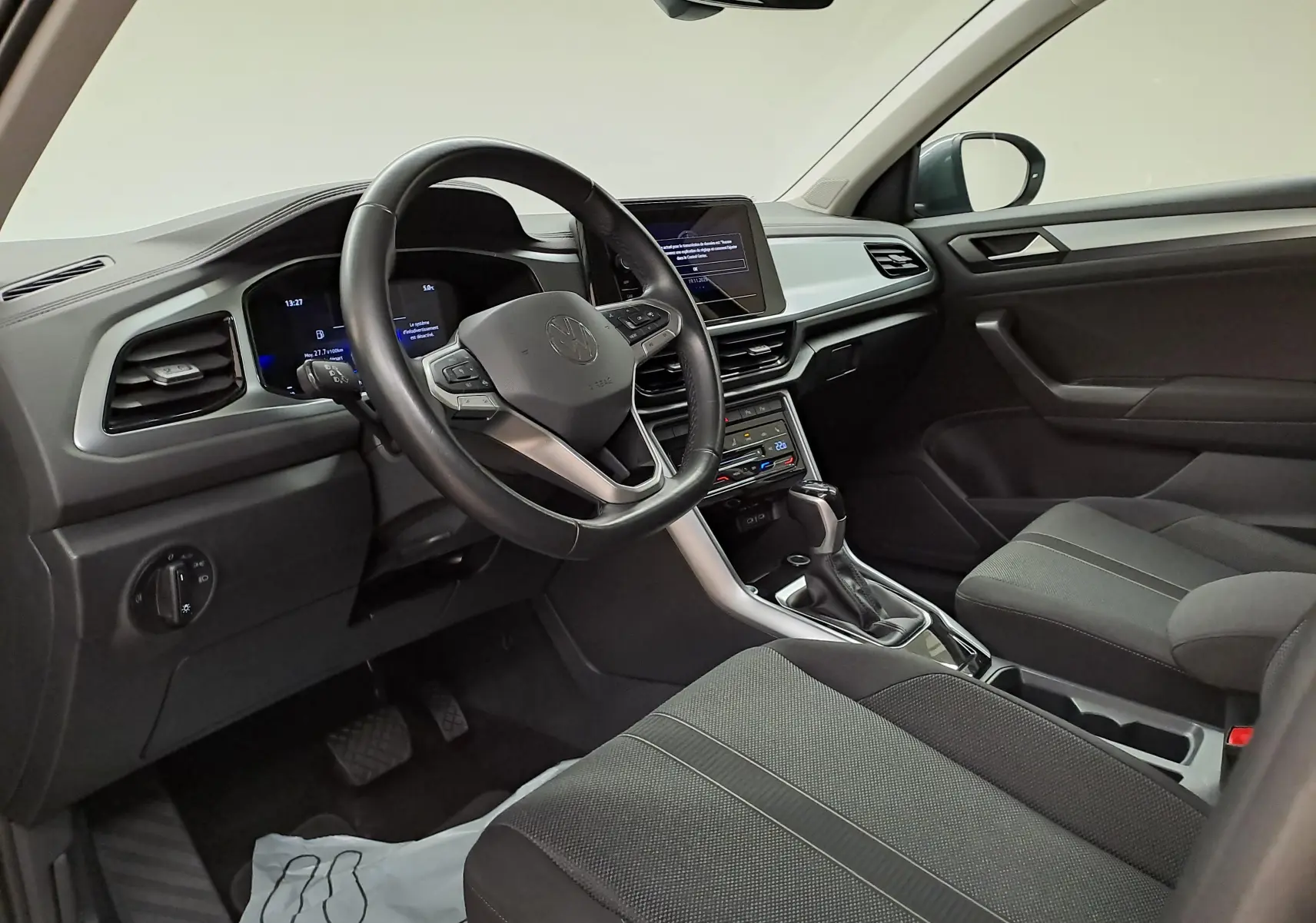 Intérieur avant droit du Volkswagen T-Roc 1.5 TSI 150 DSG7 Life avec tableau de bord moderne et volant multifonction noir.