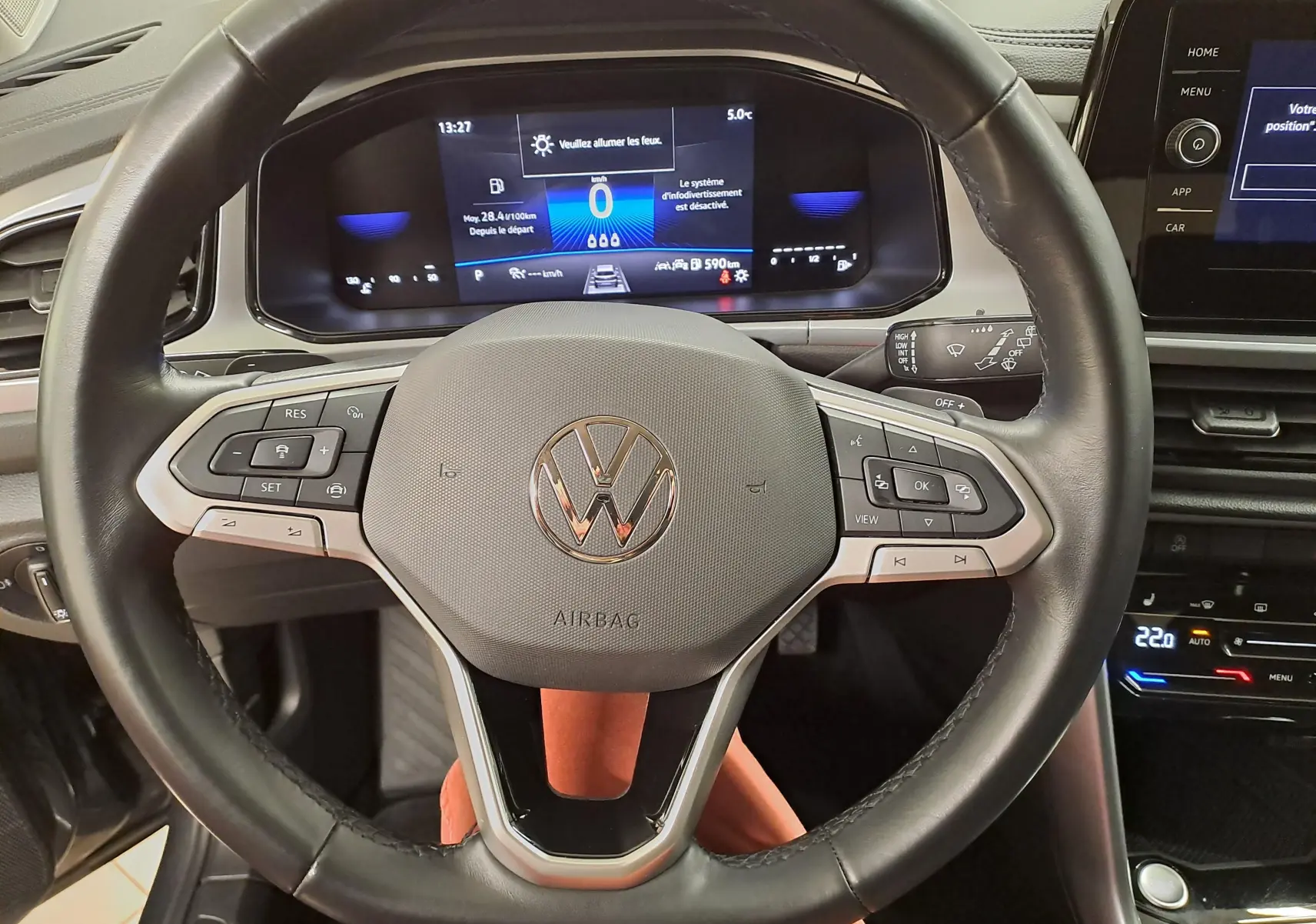 Vue rapprochée du volant cuir noir du Volkswagen T-Roc 2024 avec tableau de bord numérique et commandes intégrées.