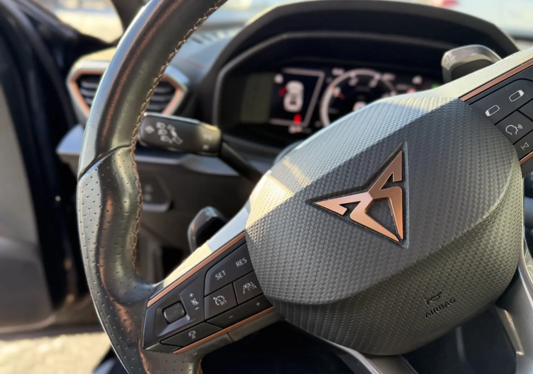 Gros plan sur le volant en cuir noir avec logo CUPRA cuivré et commandes intégrées, intérieur du Formentor 2023.