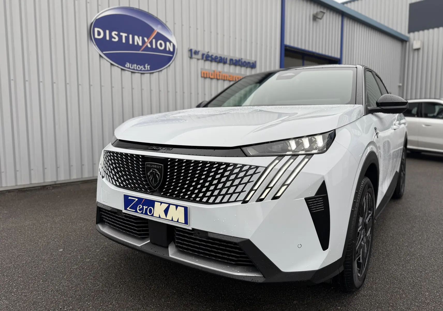 Peugeot 3008 Hybrid blanc Okenite avec toit noir, vue 3/4 avant mettant en valeur la calandre distinctive et les phares LED.