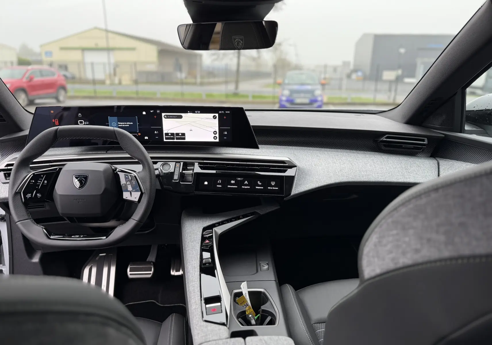 Vue intérieure avant du Peugeot 3008 Hybrid 2025, tableau de bord moderne avec écran large et volant compact noir.