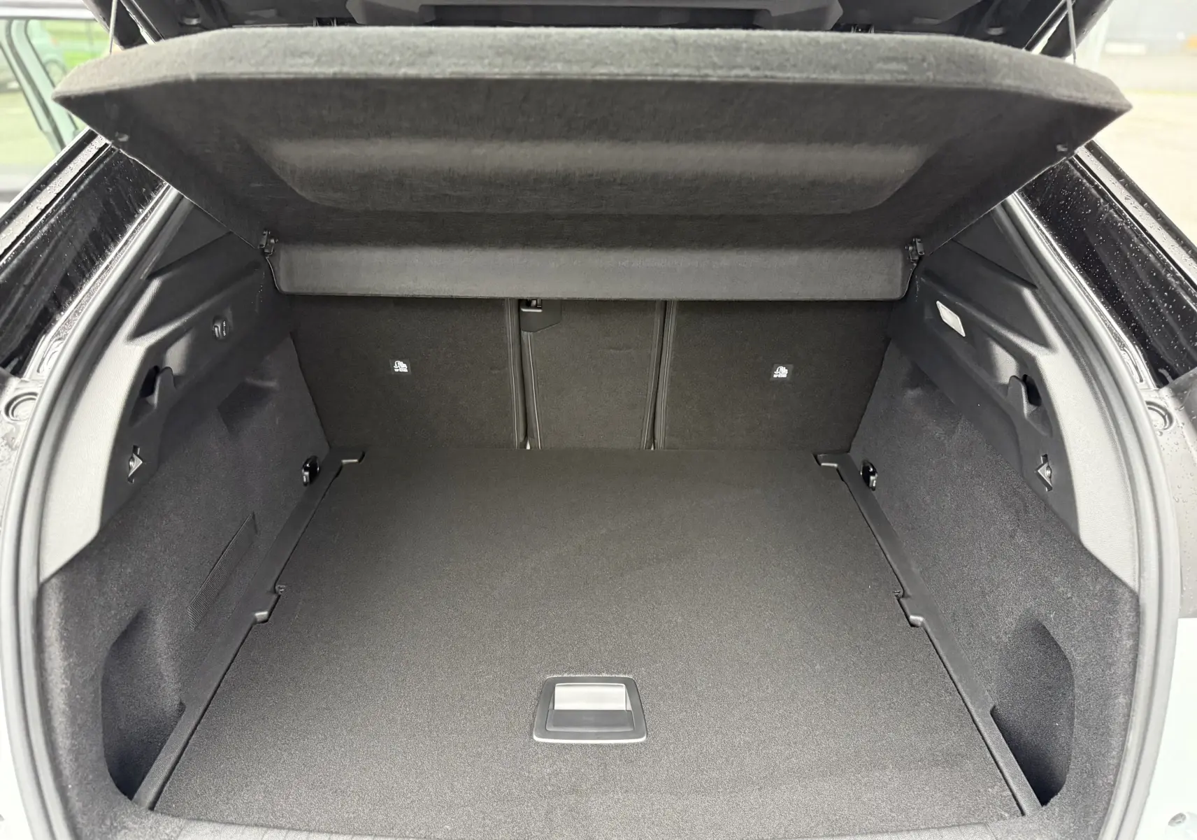 Coffre ouvert du Peugeot 3008 Hybrid blanc, vue arrière montrant un espace de chargement spacieux et bien fini.