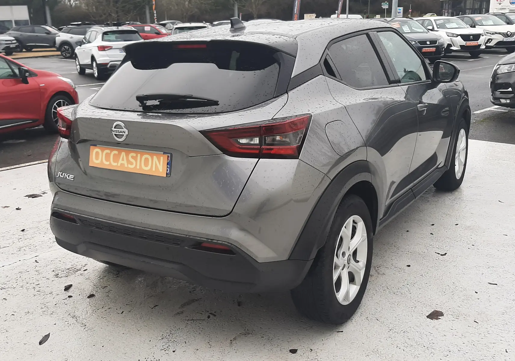 Vue 3/4 arrière droite d'un Nissan Juke gris 2020 avec feux arrière LED et plaque "OCCASION" visible.