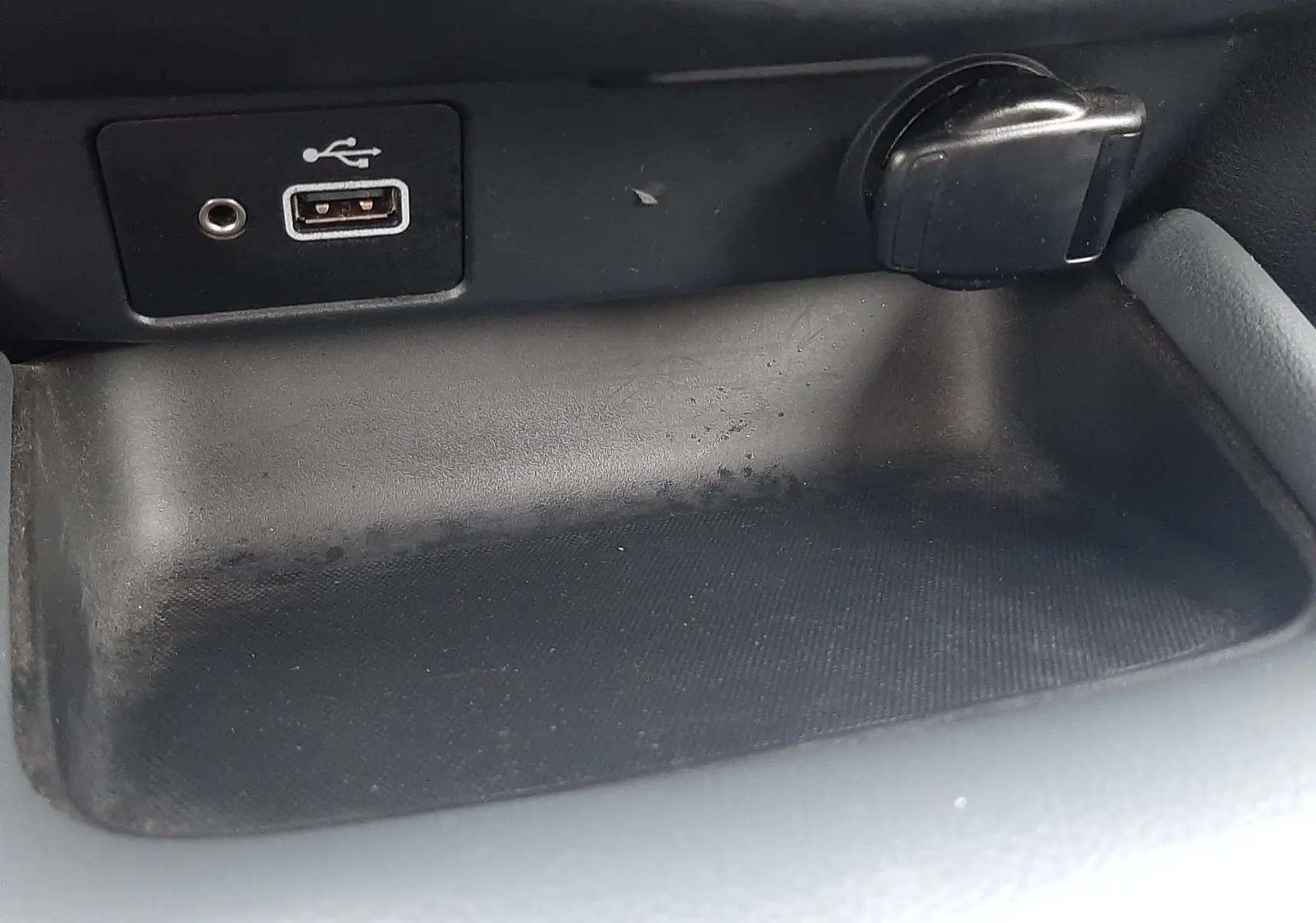 Vue rapprochée de la console centrale du Nissan Juke gris 2020, montrant une prise USB et un allume-cigare.