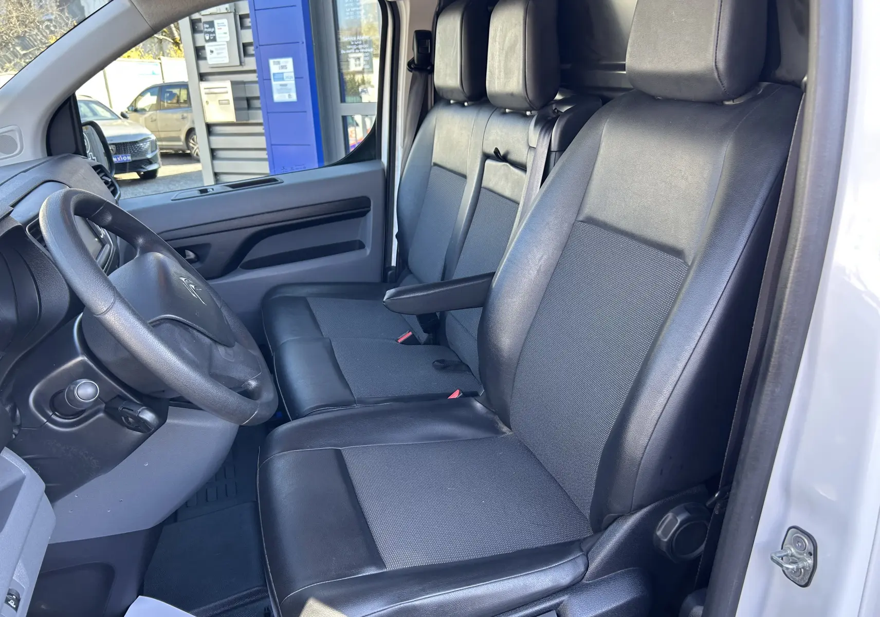 Vue intérieure côté conducteur du Citroën Jumpy blanc 2017, sièges en cuir noir et tableau de bord simple.