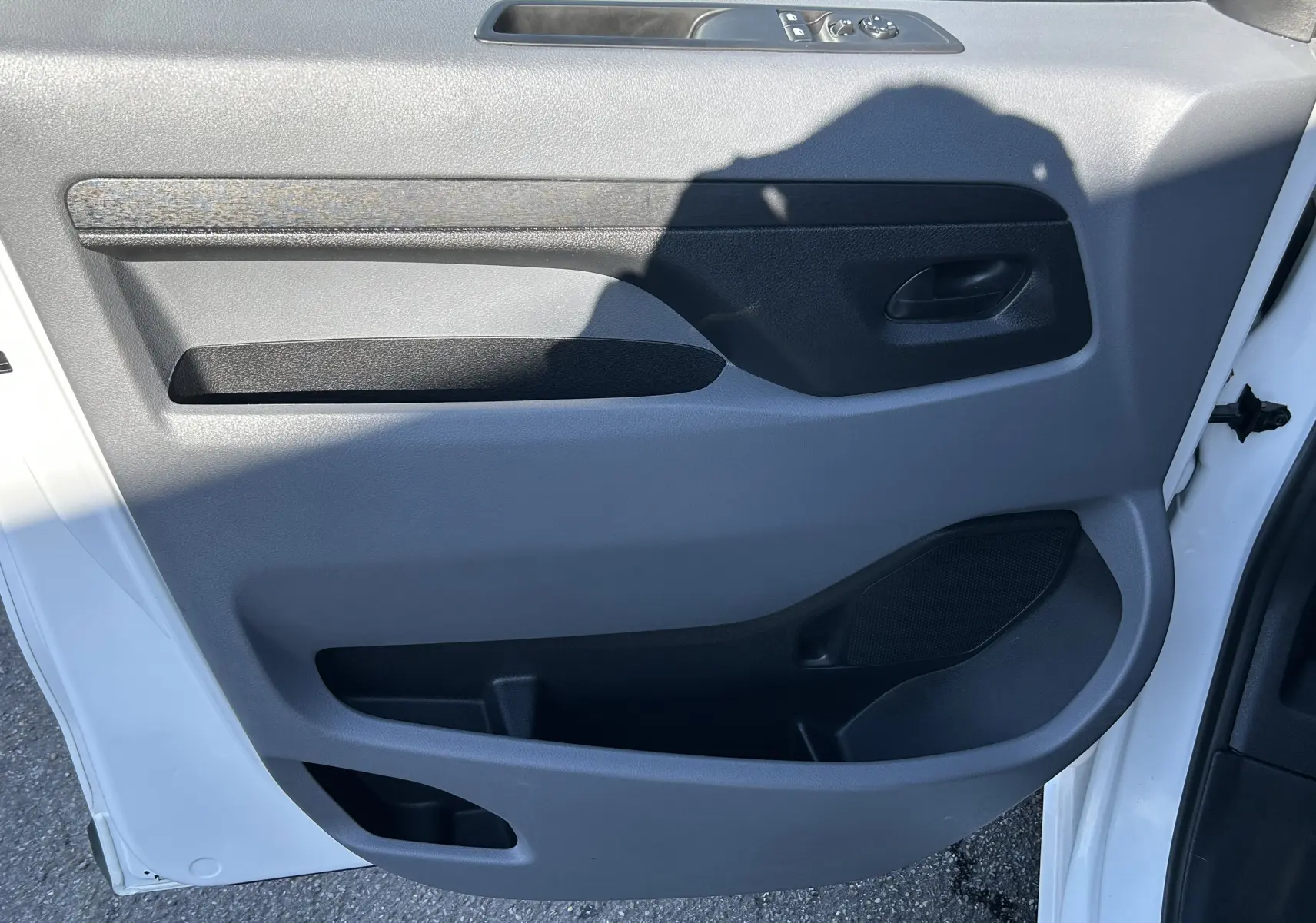 Vue intérieure de la porte avant gauche blanche du Citroën Jumpy 2017 avec panneaux gris et commandes de vitres.