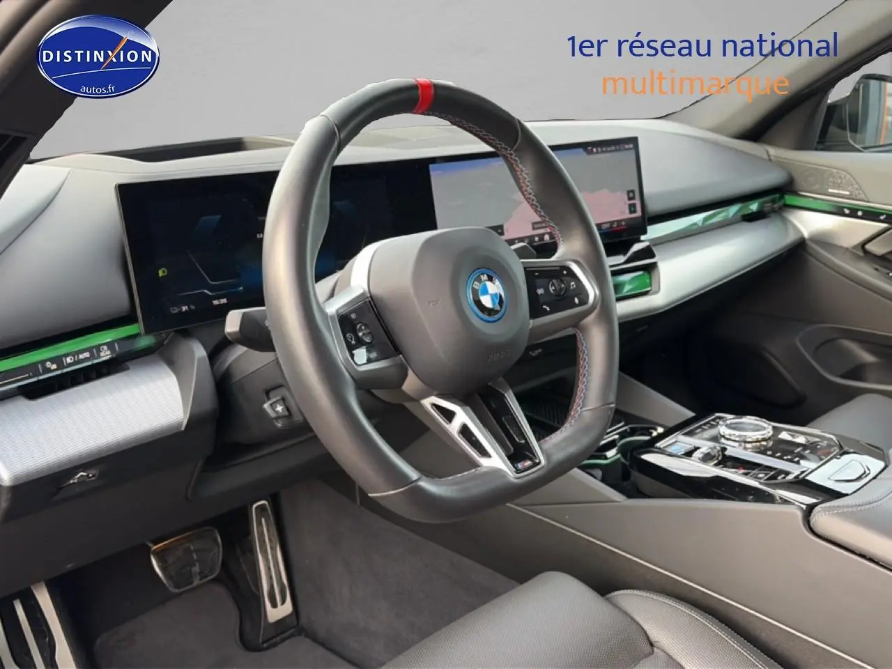 Vue intérieure côté conducteur du tableau de bord et volant cuir sport de la BMW Série 5 i5 M60 noir avec écran tactile et inserts verts.