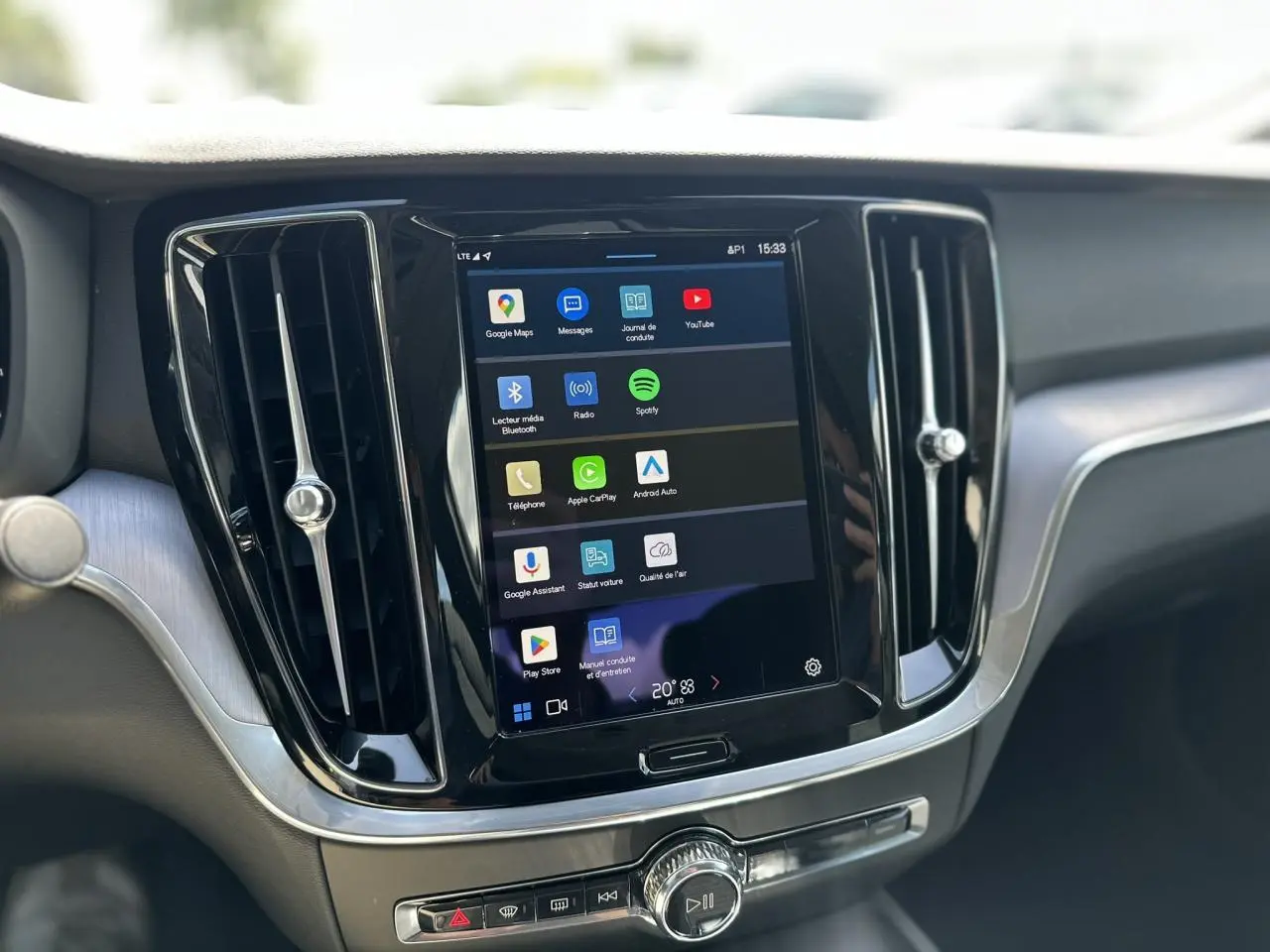 Écran tactile central du tableau de bord du Volvo S60 gris Platinium, avec commandes multimédia et aérateurs noirs.