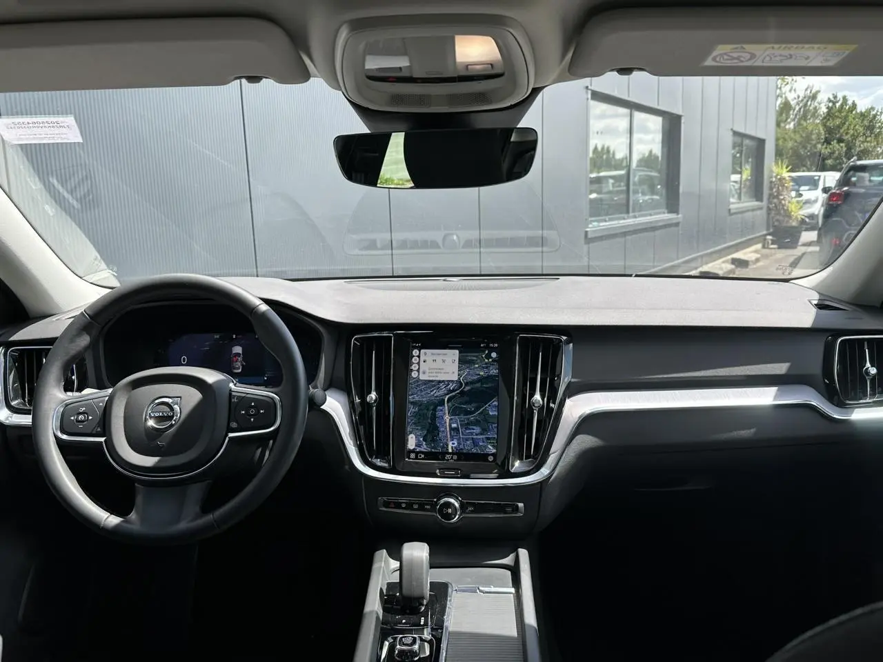 Vue intérieure du tableau de bord de la Volvo S60 2024 avec écran tactile GPS et volant multifonction noir.