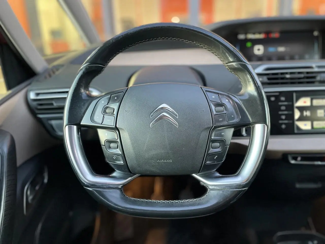 Gros plan sur le volant multifonction noir du Citroën C4 Picasso 2014, avec tableau de bord et écran tactile en arrière-plan.